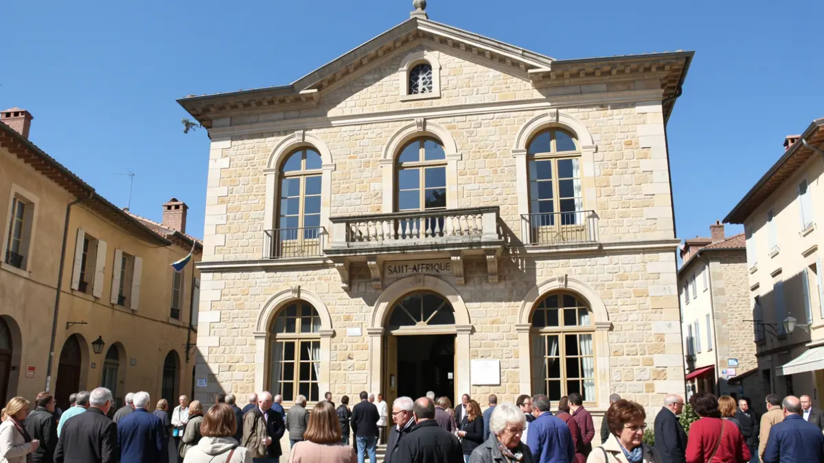 Facade of the Saint-Affrique town hall, a stone building with a balcony and arched windows, under a clear blue sky.