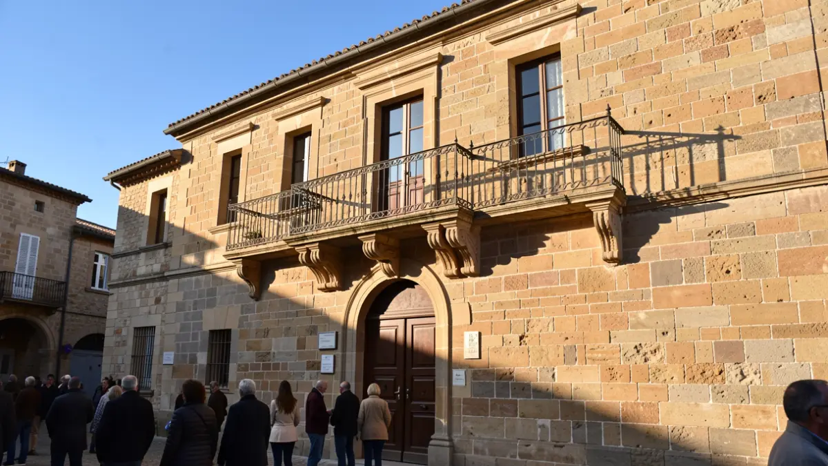 Image générique de la façade d'un hôtel de ville en pierre du Sud de la France, avec balcon et balustrade en fer forgé, sous le soleil de l'après-midi.