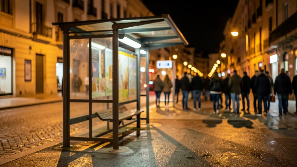 Generic image of a night bus stop in an Occitanie city, with warm streetlights and shadows on the wet pavement.