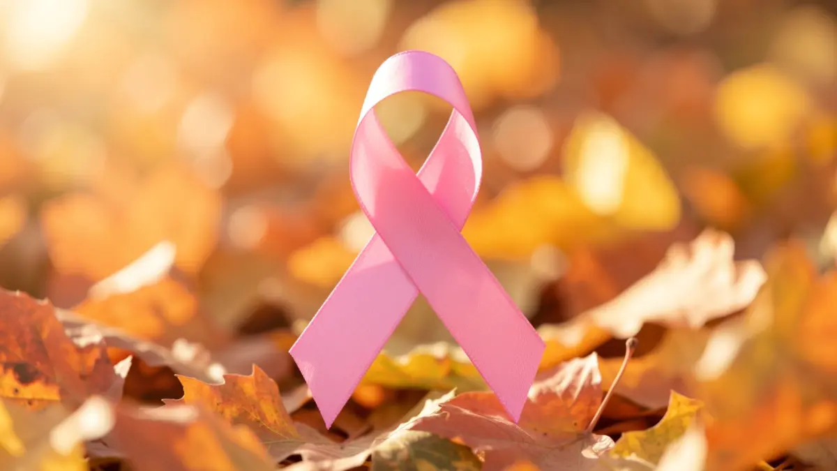 Pink ribbon symbol for 'Octobre Rose' on a background of autumn leaves.